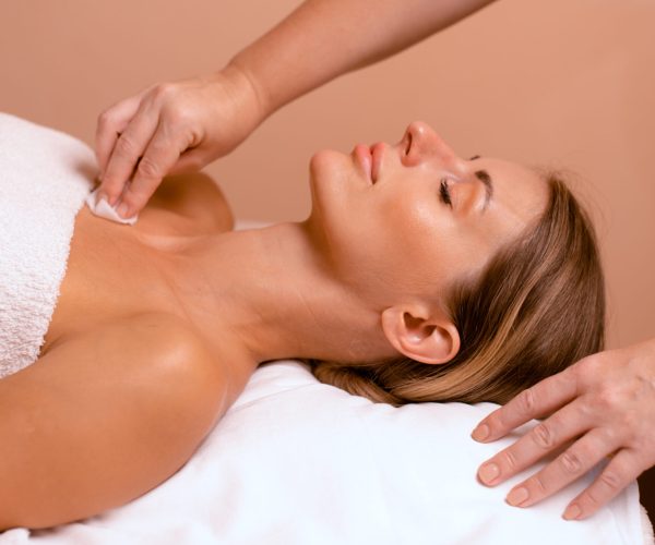 preparation of neck skin and decollete zone before procedure in beauty salon. Beautician hands clean skin